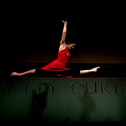 Natasha mid-leap on stage in a red dress