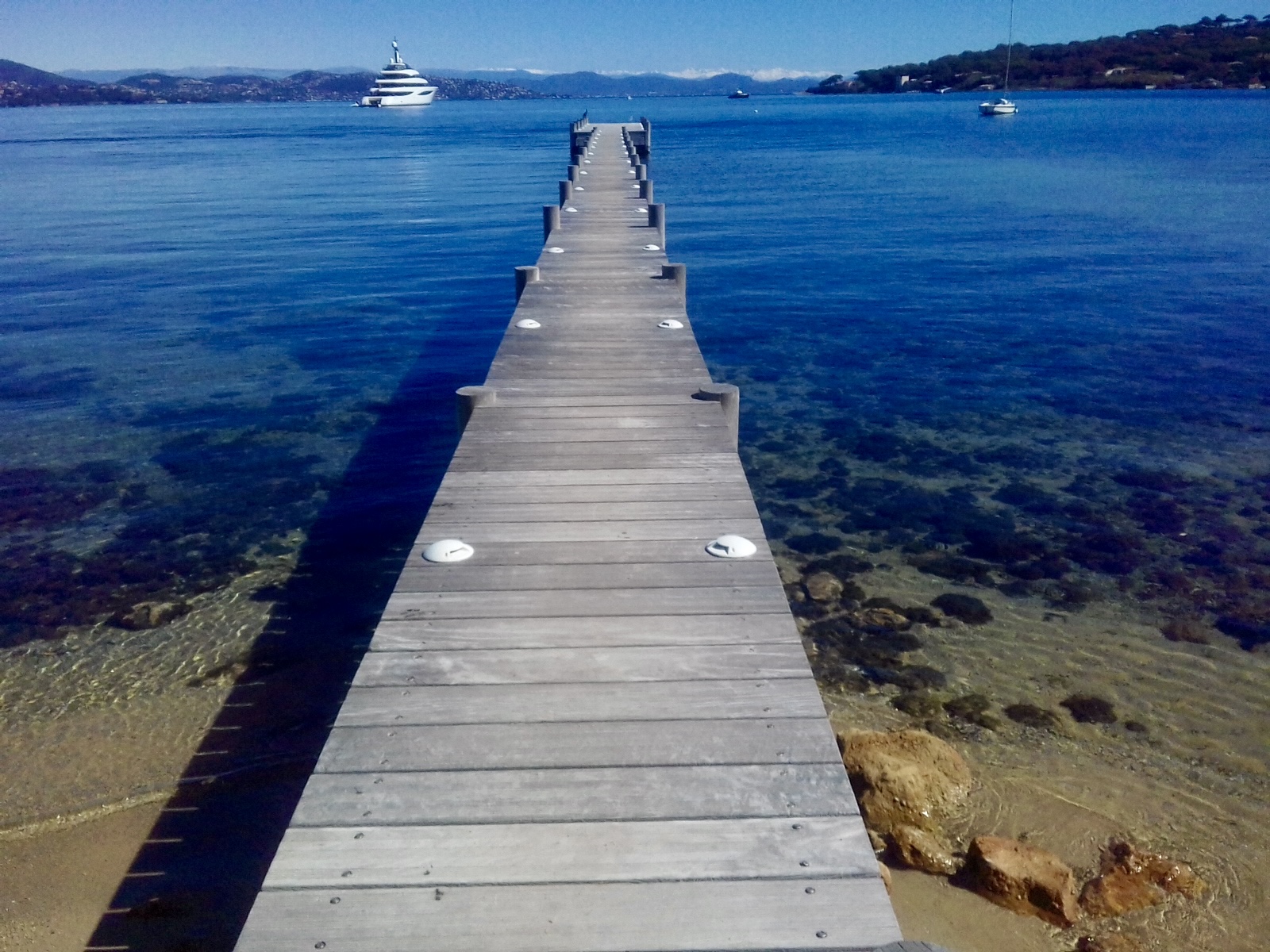 Long wooden jetty stretching into deep blue Mediterranean water near Saint-Tropez