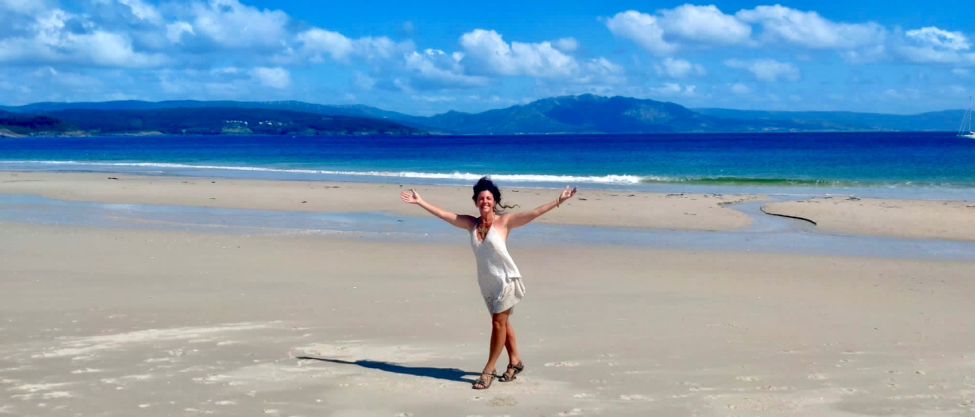 Arms wide open on a wide empty beach at the end of the Camino, Galicia