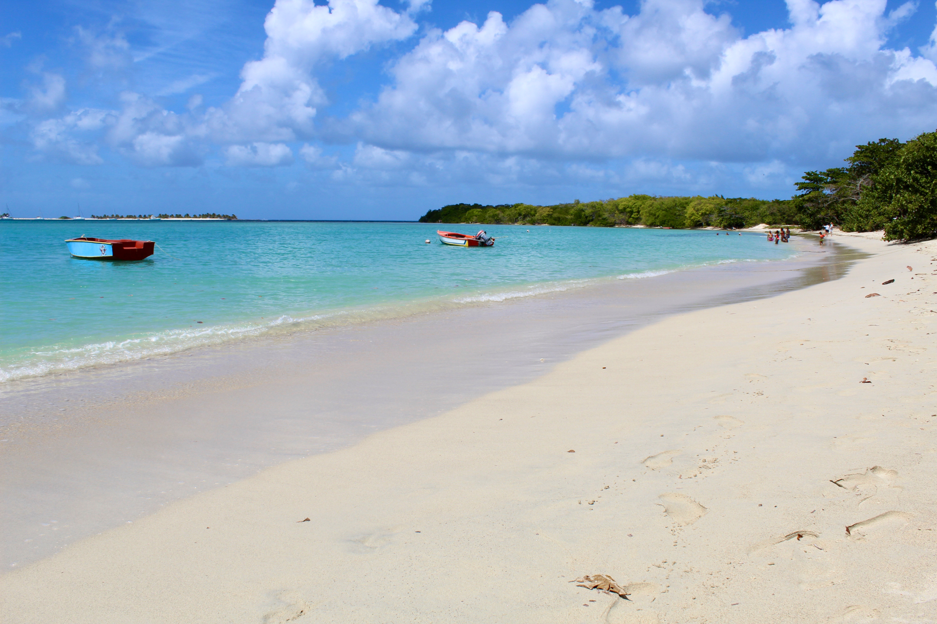 Turquoise Caribbean bay with wooden fishing boats and white sand beach