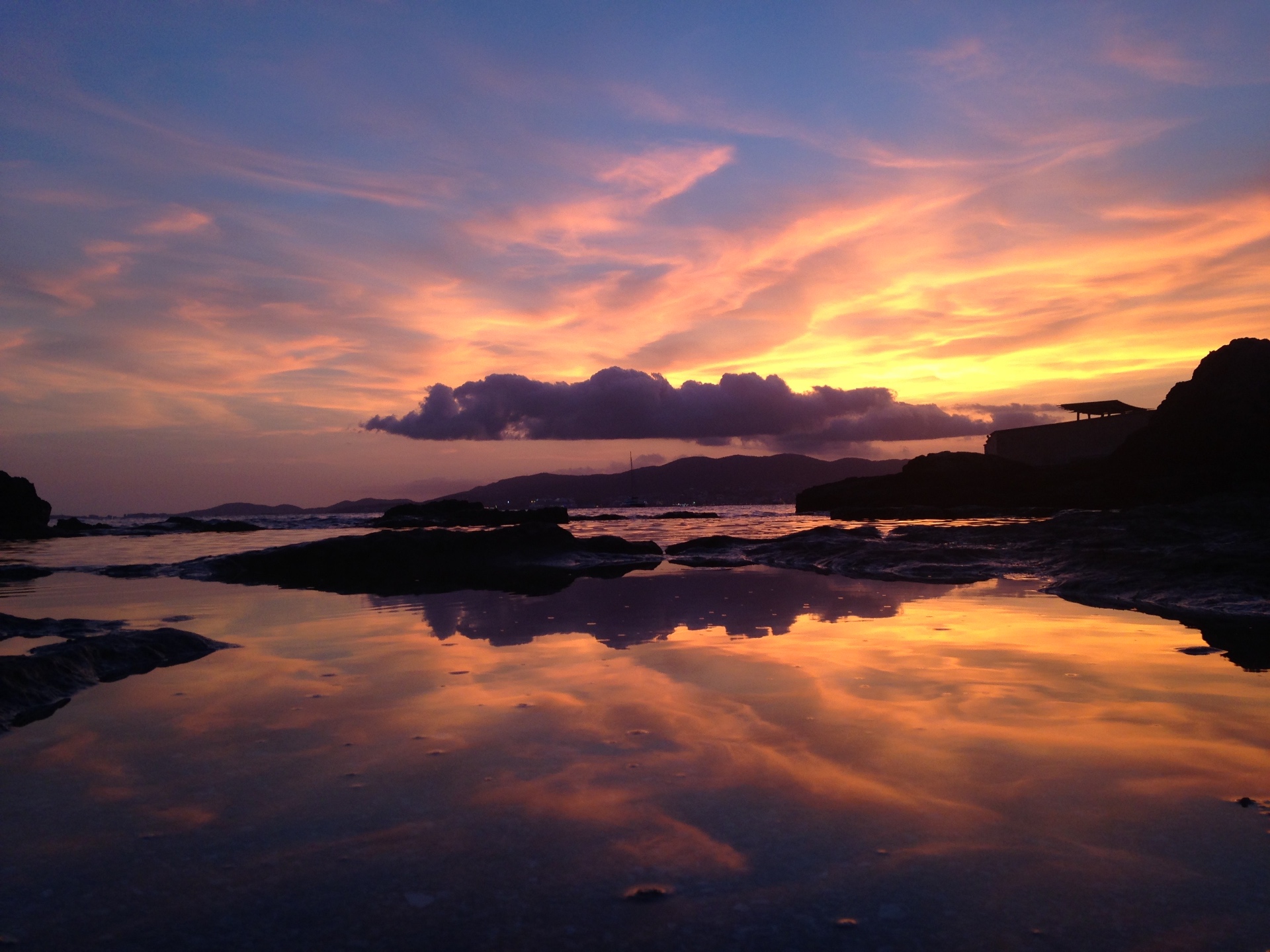 Pink and orange Mediterranean sunset reflected in a tide pool, Ibiza