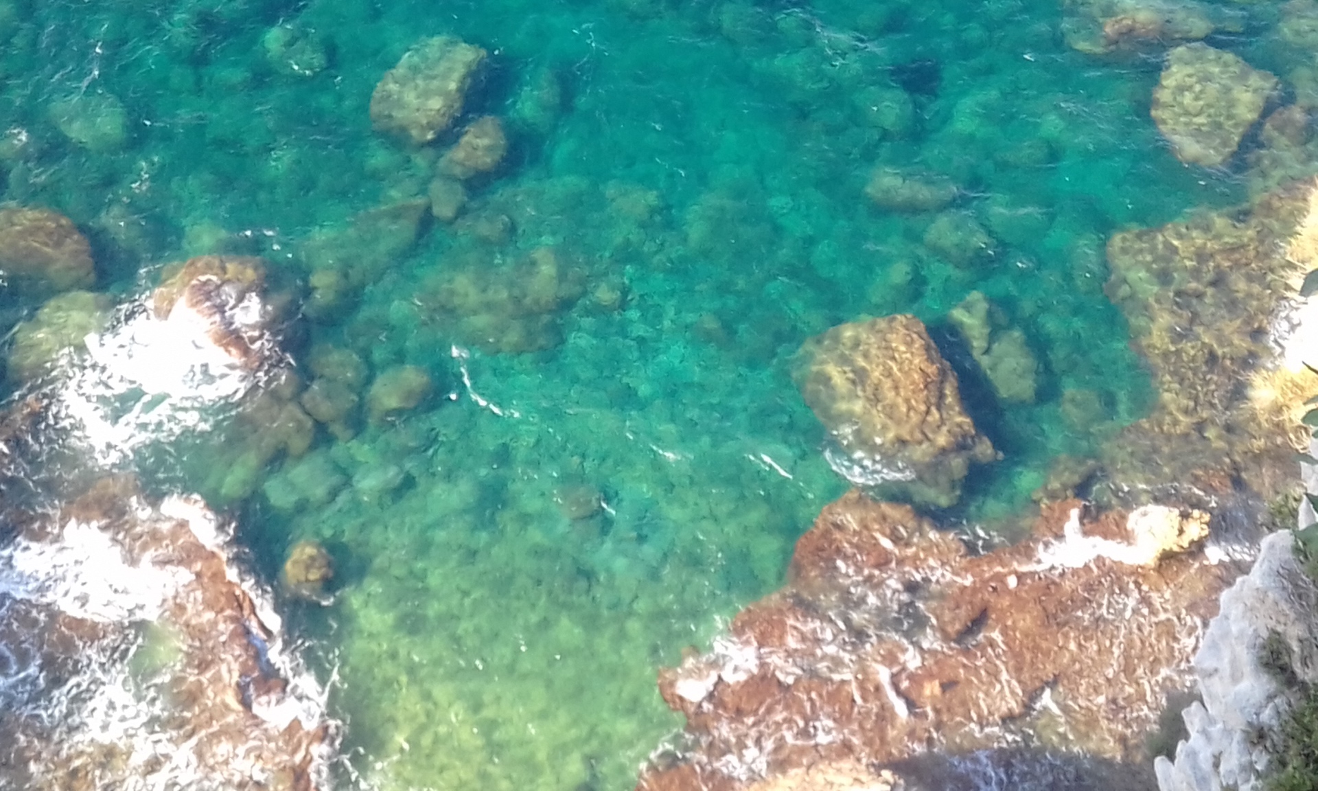 Crystal clear turquoise water over rocks seen from above